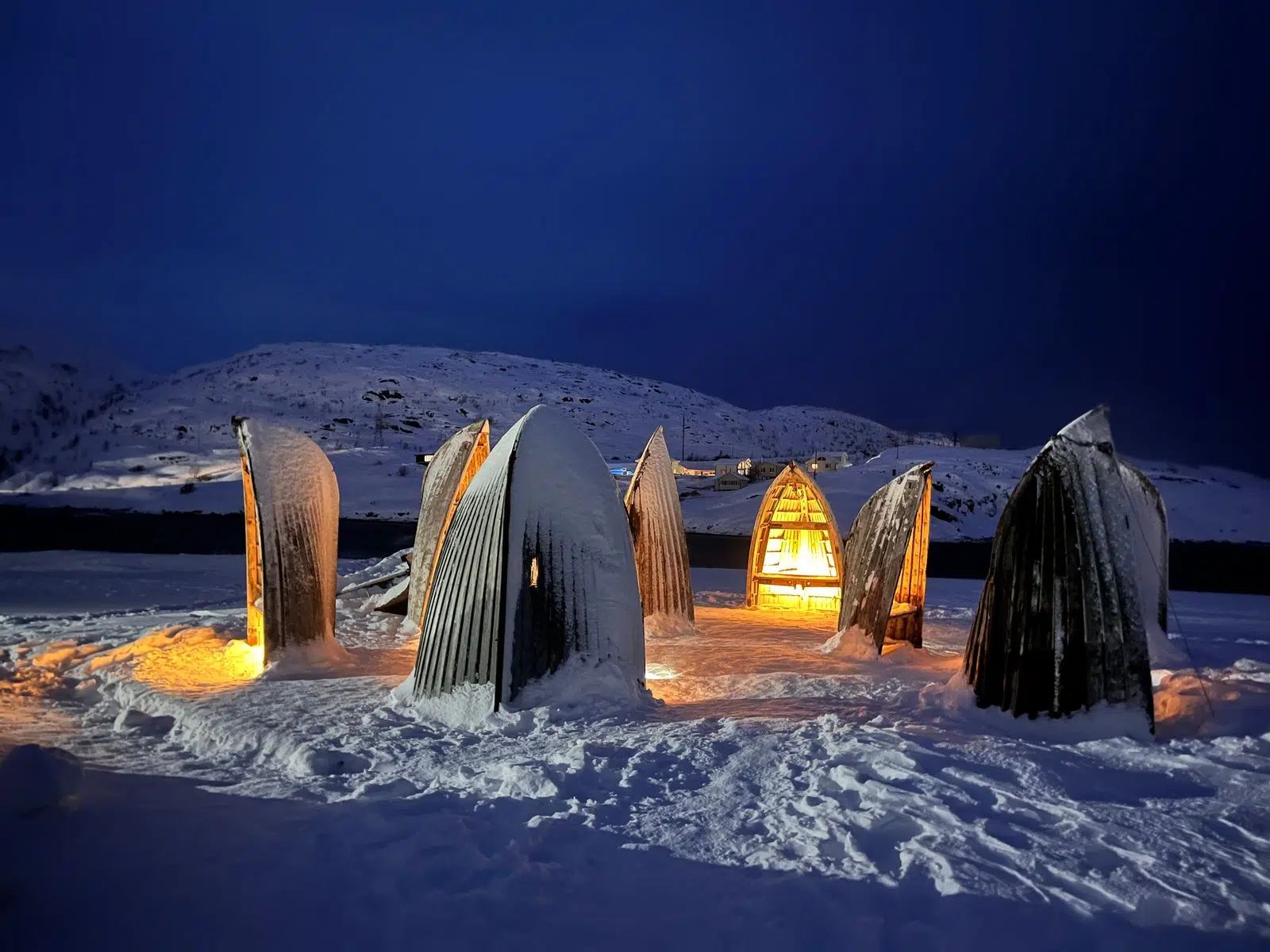 Illuminated whale-tail sculptures beside a snowy Arctic bay