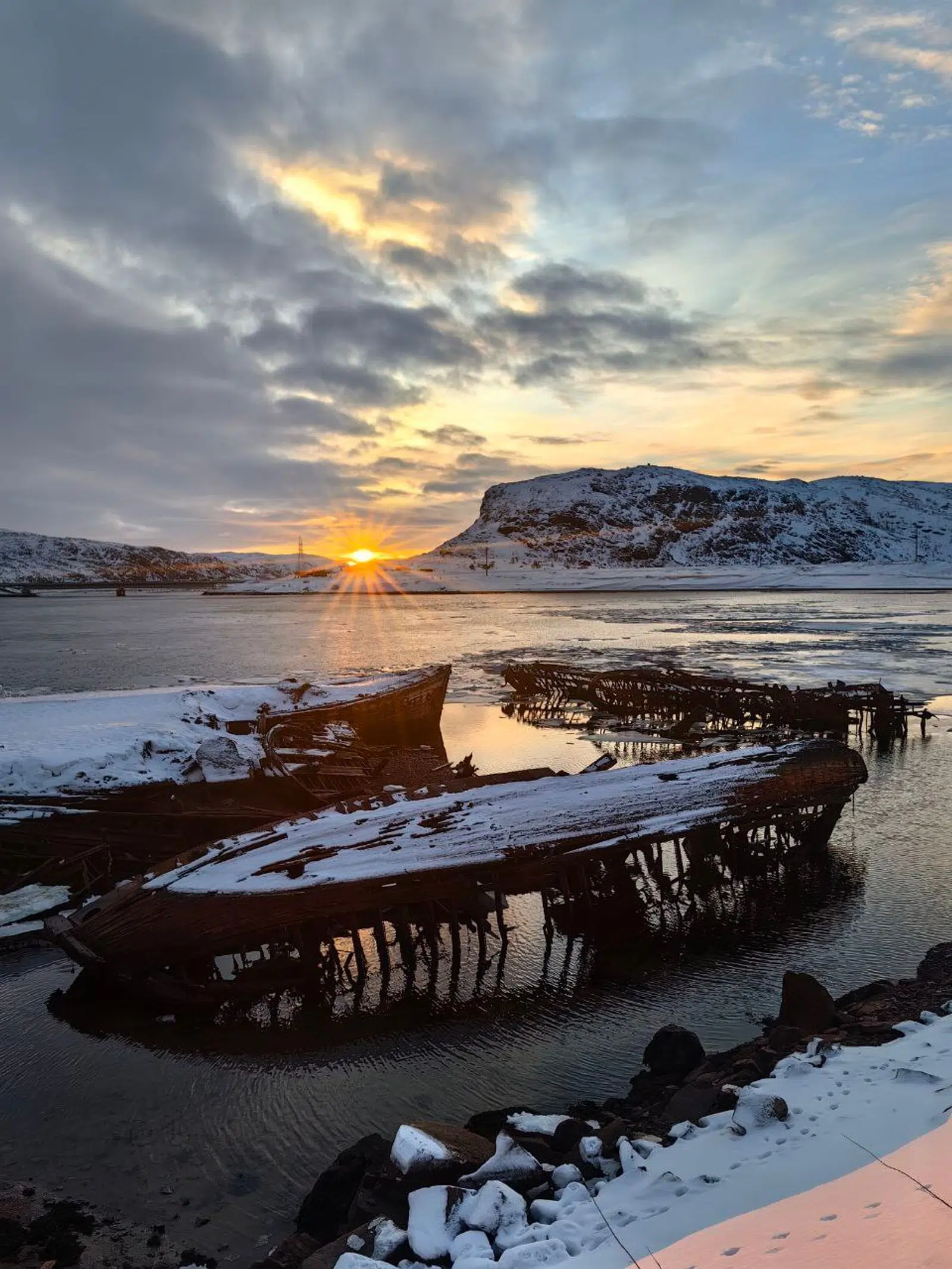 Old wooden boat remains on the snowy shore at Teriberka