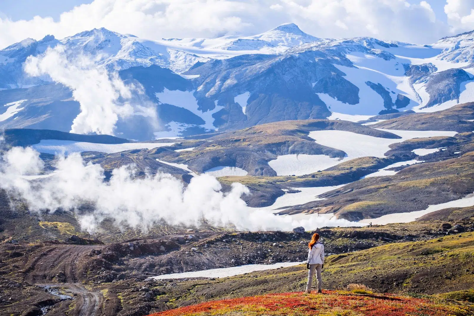 A traveler overlooking a steaming volcanic valley