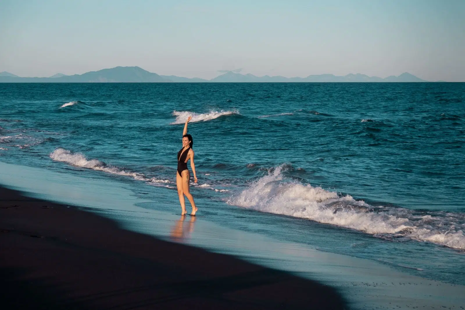 A traveler walking at the edge of the Pacific on Khalaktyrsky black-sand beach