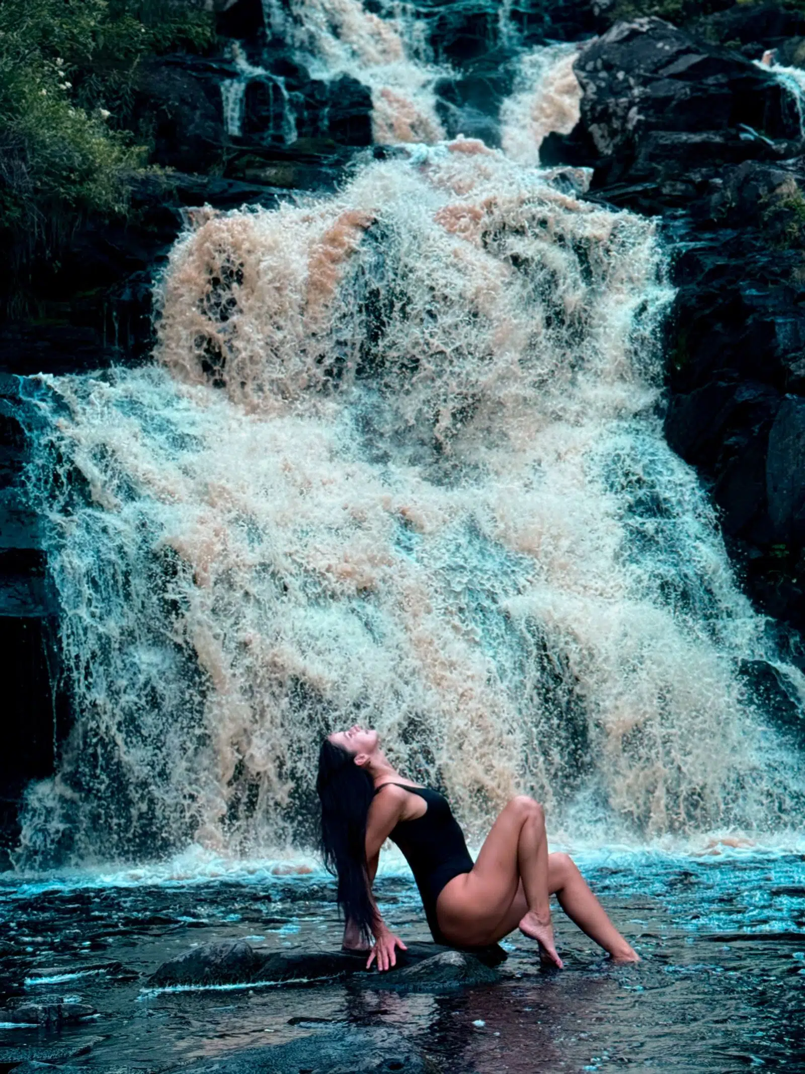 Traveler posing in front of a broad white waterfall