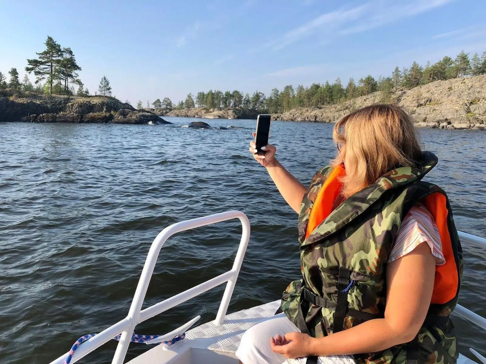 Traveler in a life jacket photographing the Ladoga skerries from a boat