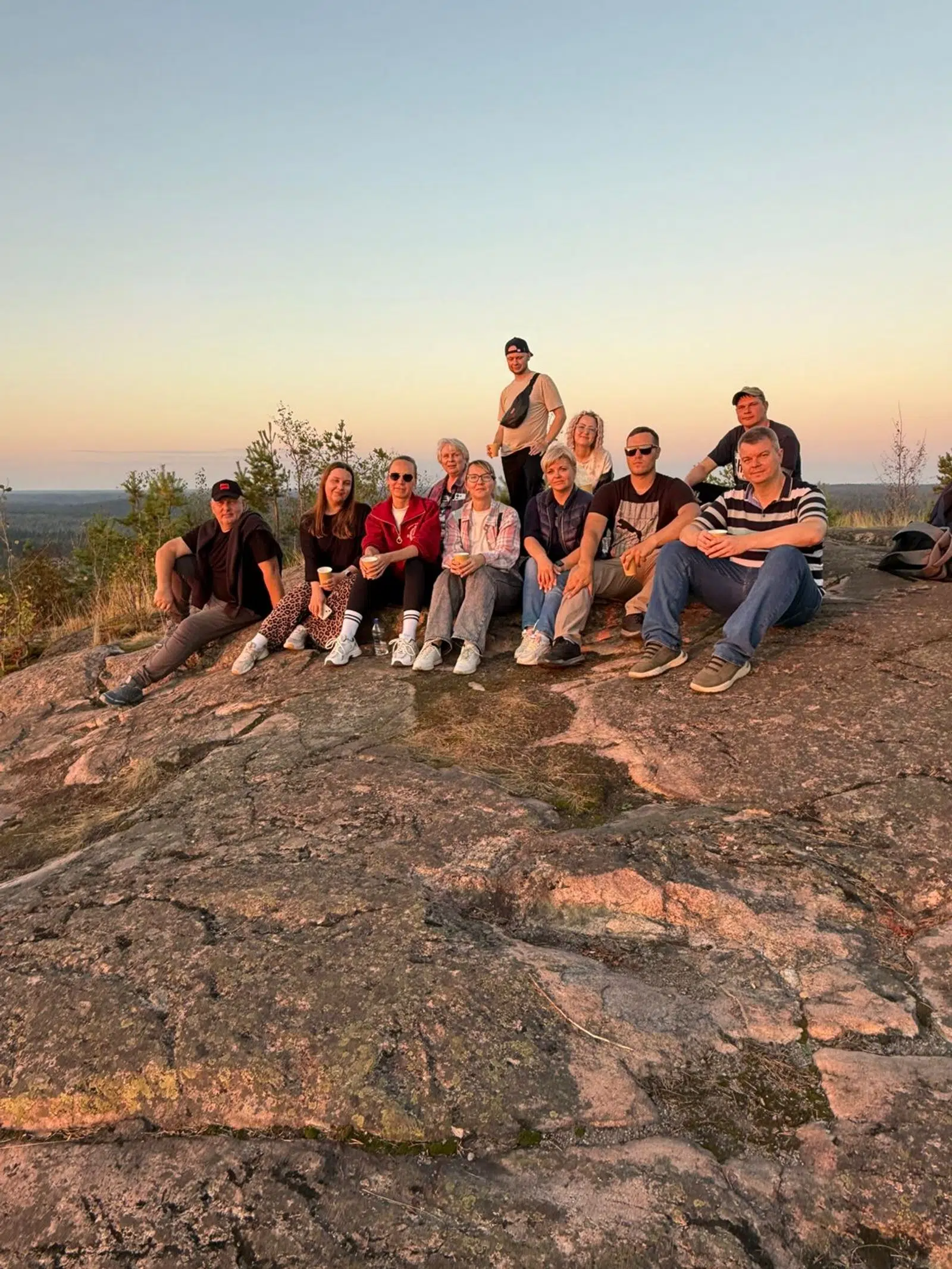 Tour group seated together on a rocky hill at sunset