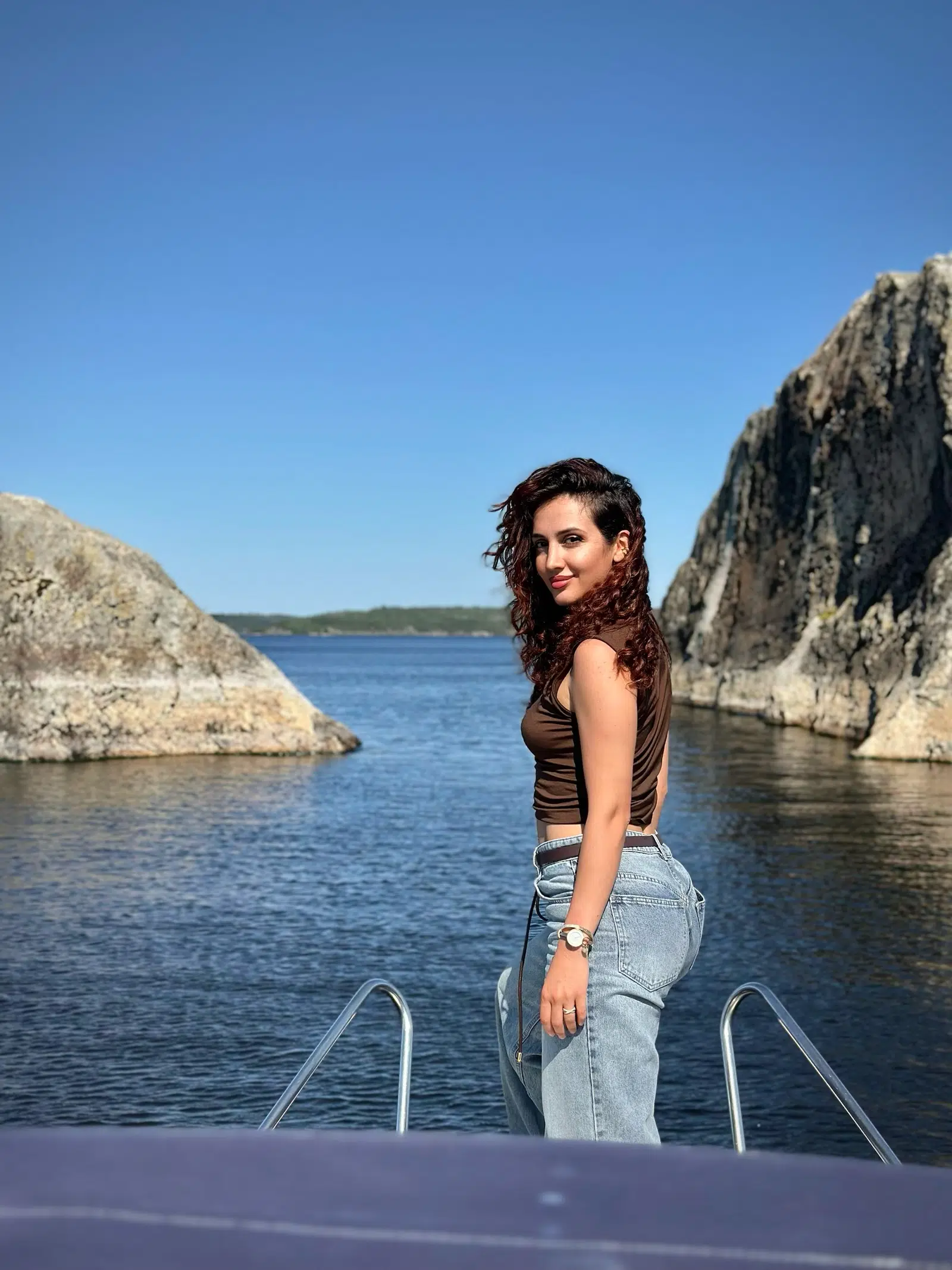 Traveler looking across a blue lake from the bow of a boat
