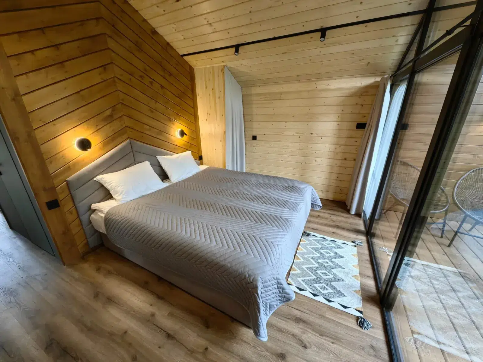 Warm wood-lined cabin bedroom with a large window