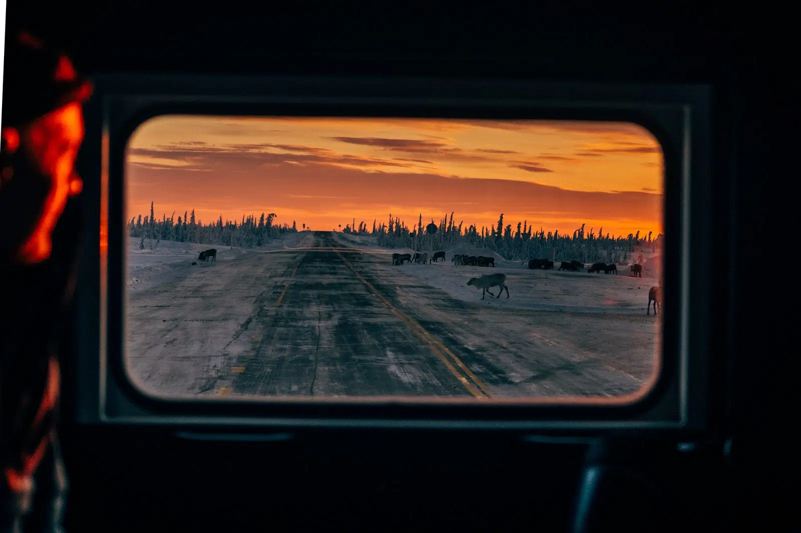 Sunset over the winter road seen through an all-terrain vehicle window