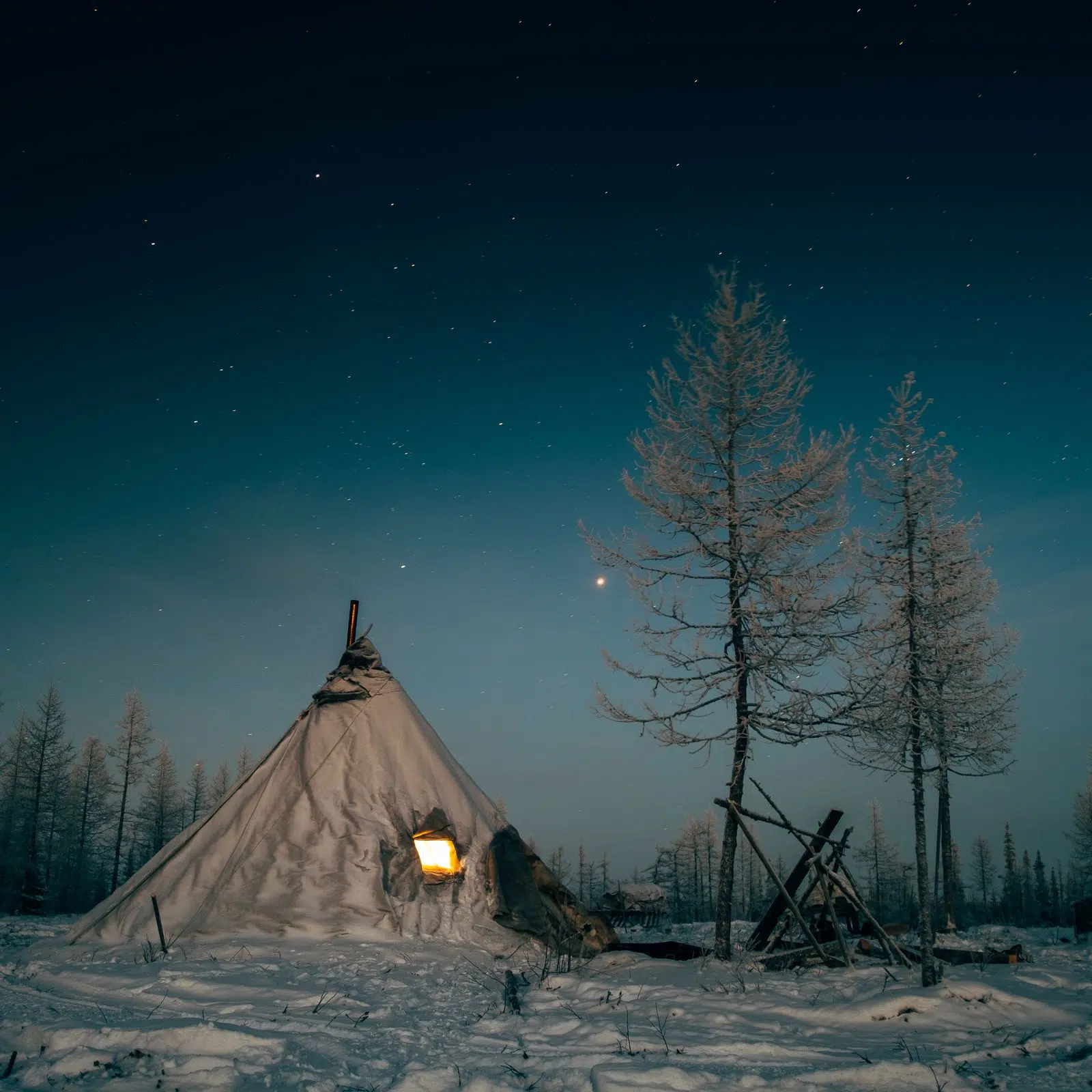 Traditional Nenets chum lit from within under the winter night sky