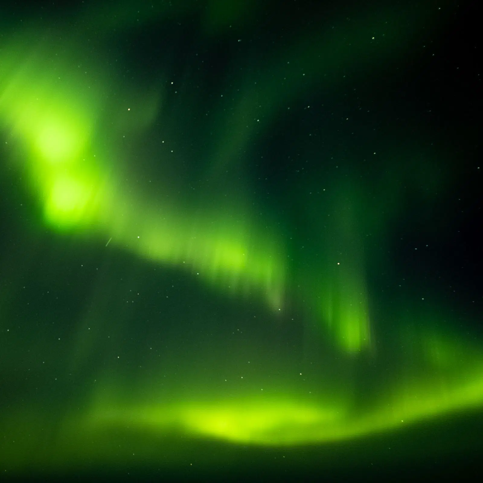 Bright green aurora rippling across the night sky