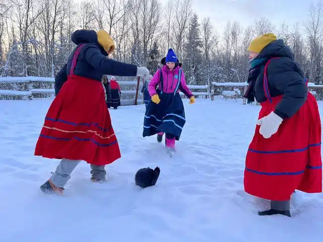Travelers in colorful traditional clothing playing outdoors in deep snow