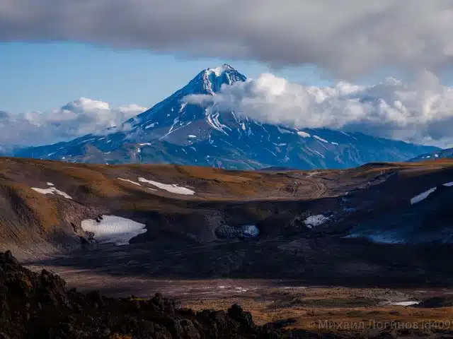 A snow-streaked Kamchatka volcano beneath low clouds