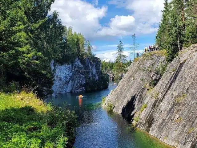 Boats moving through a narrow green marble canyon in Karelia