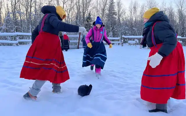 Travelers in colorful traditional clothing playing outdoors in deep snow