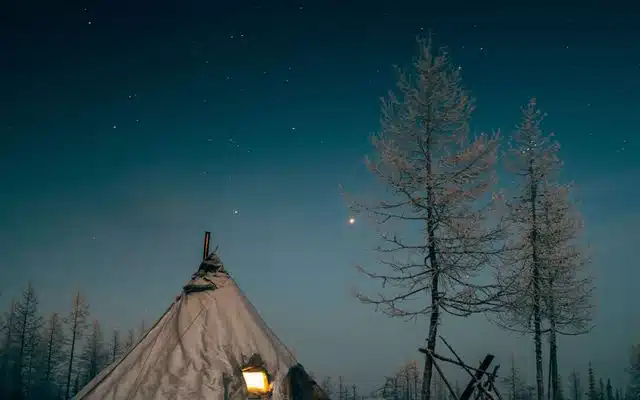 Traditional Nenets chum lit from within under the winter night sky
